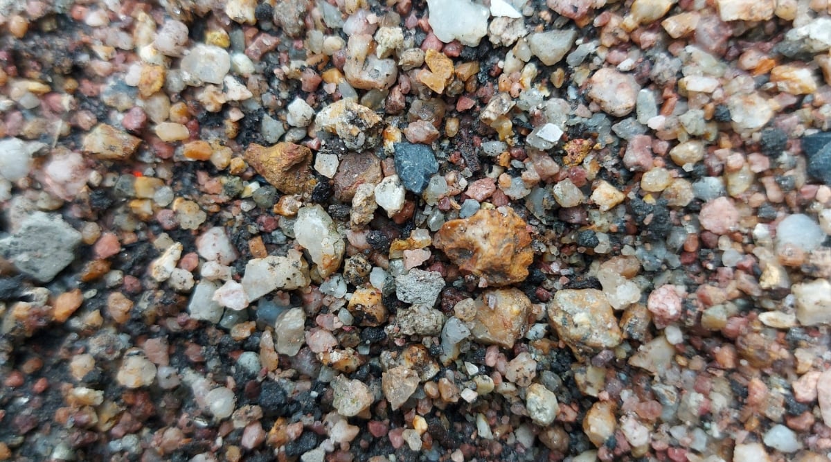 A combination of fine sand, coarse gravel, and gritty particles in earthy hues, forming a balanced mix for aloe. The sand appears fine-grained, the gravel shows varying sizes, and the grit offers a textured, blended composition.
